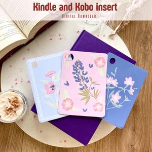 Op de afbeelding: Drie Kindle- en Kobo-inzetstukken met bloemmotieven in pastelkleuren. Eén is lichtblauw met roze bloemen, een andere is roze met blauwe bloemen en de derde is blauw met witte bloemen. De tekst "Kindle and Kobo insert" staat bovenaan.