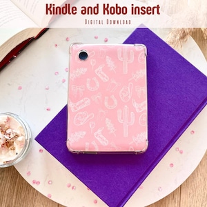 Op de afbeelding: Een roze Kindle- of Kobo-hoesje met een doorzichtige behuizing, met een wit patroon van cactussen, hoefijzers en cowboyhoeden. Het hoesje ligt op een paars boek, met een open boek en een kleine glazen kom. Tekst: "Kindle and Kobo insert".