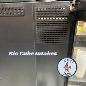 Pu&ograve; includere: Primo piano di un filtro per acquario nero con due bocchette di aspirazione. Il testo "Bio Cube Intakes" &egrave; stampato sulla parte anteriore del filtro. Un adesivo rotondo con il testo "Lid Propz Shop" e un'illustrazione di un pesce si trova sul lato destro del filtro.