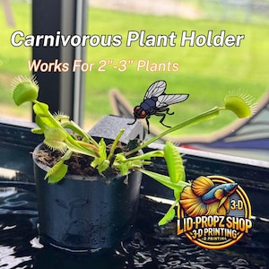 May include: A black 3D printed plant holder for carnivorous plants, designed to hold plants 2 to 3 inches in diameter. The holder is shown with a Venus flytrap plant and a fly. The text "LID-PROPZ SHOP 3-D PRINTING" is visible in the image.