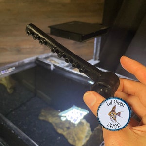 Close-up of upgraded spray bar showing multiple flow holes and curved design. Snaps into stock nozzle location for better flow control in Fluval Flex or EVO tanks.