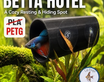 Puede incluir: Un túnel cilíndrico negro para acuario con la etiqueta BETTA HOTEL A Cozy Resting & Hiding Spot y el texto PETG. Un pez betta azul y rojo está dentro del tubo, que cuenta con dos ventosas transparentes para fijarlo al tanque.