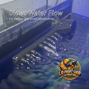 May include: A black plastic water flow diffuser with multiple small holes, creating a gentle stream of water bubbles in a blue aquarium. The text "Slows Water Flow" and "For bettas and small inhabitants" is visible above the diffuser. The text "3-D LID-PROPZ SHOP 3-D PRINTING" is visible in the lower right corner of the image.