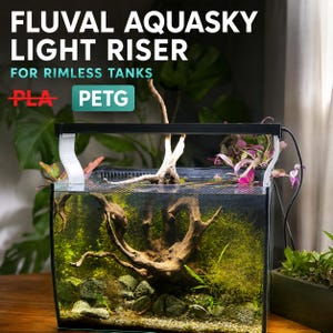 May include: A white Fluval Aquasky light riser for rimless tanks, featuring the text FLUVAL AQUASKY LIGHT RISER FOR RIMLESS TANKS, a crossed-out PLA label, and a PETG label. The riser supports a black light bar over a glass aquarium tank.