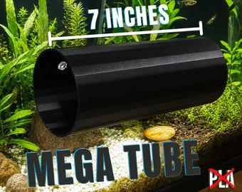 Puede incluir: Un tubo cilíndrico negro para acuario con interior hueco y un pequeño cierre metálico cerca de la abertura. El tubo está etiquetado como Mega Tube de 17,78 cm, indicando su longitud. El objeto está colocado horizontalmente en un acuario.