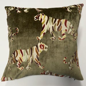 Könnte beinhalten: Quadratisches olivgrünes Zierkissen mit einem sich wiederholenden Muster stilisierter Tiger. Die Tiger haben farbenfrohe Streifen in Rot-, Gelb- und Brauntönen. Das Kissen hat eine weiche, samtige Textur und verleiht jedem Raum einen Hauch von Luxus.