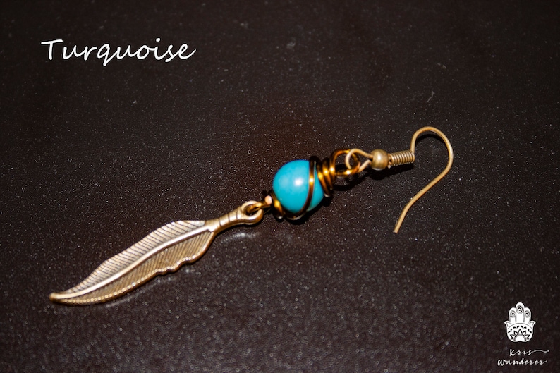 May include: Turquoise blue gemstone bead wrapped in gold wire with a silver feather charm hanging from it. The earring has a gold hook.