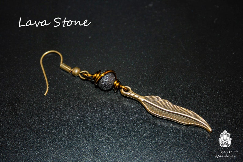 May include: A pair of earrings with a black lava stone bead and a gold feather charm. The earrings are made with gold wire and have a hook closure.