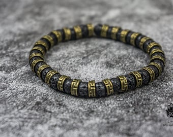 May include: A black lava rock bracelet with gold-toned metal beads. Each bead features a geometric pattern.