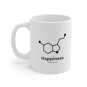 Puede incluir: Taza de cerámica blanca con un contorno negro de la molécula de serotonina y el texto "Happiness (Serotonin)"