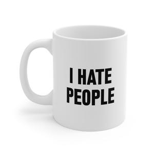 Puede incluir: Taza de cerámica blanca con asa curva. La taza presenta el texto negro "I HATE PEOPLE" en una fuente en negrita sin serifa. La taza está diseñada para bebidas calientes y es adecuada para uso doméstico u oficina.