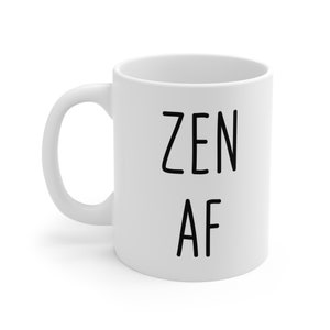Puede incluir: Taza de cerámica blanca con las palabras "ZEN AF" impresas en letras negras y en negrita. La taza tiene un asa curvada y un diseño sencillo, adecuada para café, té o cualquier bebida.