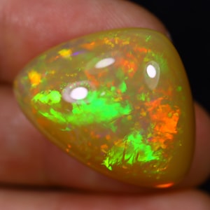 May include: A yellow opal cabochon with green and orange flashes of color.
