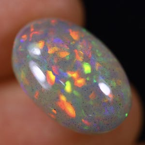 Könnte beinhalten: Ein weißer Opal-Edelstein mit durchscheinendem, milchigem Aussehen. Der Opal zeigt eine Vielzahl von Farben, darunter Orange, Gelb, Grün und Blau.