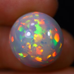 May include: A white opal sphere with a rainbow of colors, including green, orange, and red.