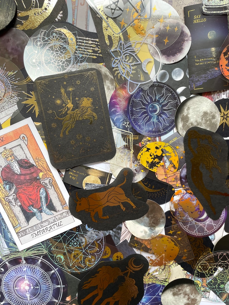 May include: A collection of celestial-themed stickers and tarot cards. The stickers feature gold foil accents with moons, stars, and zodiac symbols. One tarot card displays a king, while another shows a winged figure riding a lion.