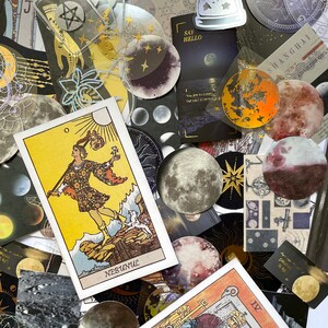 May include: A collection of celestial-themed stickers and tarot cards. The image features various moon phases, stars, and astrological symbols. Several tarot cards are visible, including one with the word "NEBUNUL". The color palette includes gold, black, and shades of purple.