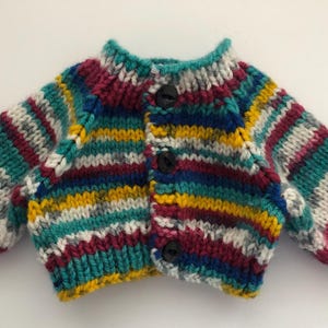 May include: A colorful, hand-knitted cardigan with horizontal stripes in teal, burgundy, yellow, and white. The sweater has a round neckline, long sleeves, and is fastened with three black buttons. The garment is made of thick yarn.