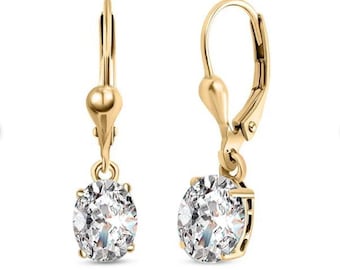 May include: A pair of gold dangle earrings with a clear round stone. The earrings have a lever back closure.