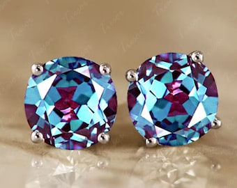 Peut inclure: Une paire de boucles d'oreilles à clous rondes avec des pierres précieuses à facettes. Les gemmes présentent un effet changeant de couleur, avec des teintes de bleu sarcelle, de violet et de bleu. Chaque boucle d'oreille est sertie d'une tige en métal argenté.