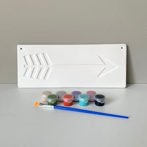 May include: A white wooden arrow sign with a paintbrush and ten small paint pots in various colors, including green, red, blue, purple, and black.
