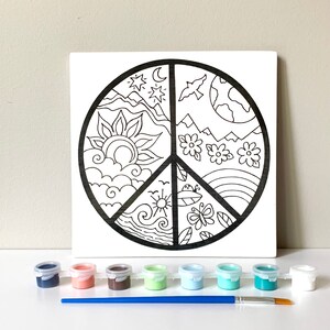 May include: A black and white peace sign design on a white canvas with a set of paint pots and a paintbrush. The peace sign is divided into four sections, each depicting a different element of nature: the sun, the sky, the earth, and the ocean.