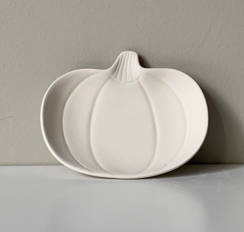 Puede incluir: Plato de cer&aacute;mica blanco con forma de calabaza. El plato est&aacute; dise&ntilde;ado para parecer una calabaza con un tallo y nervaduras.