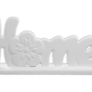 Puede incluir: Un letrero de cer&aacute;mica blanca para el hogar con un dise&ntilde;o de flor en relieve. El letrero dice "Home" en una fuente estilizada.