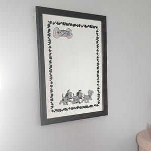 Peut inclure: Une affiche encadrée avec un fond blanc et une bordure noire de formes irrégulières. L'affiche comprend un os avec le texte "Dalmatians" et trois chiens dalmatiens de dessin animé. Le cadre est noir.