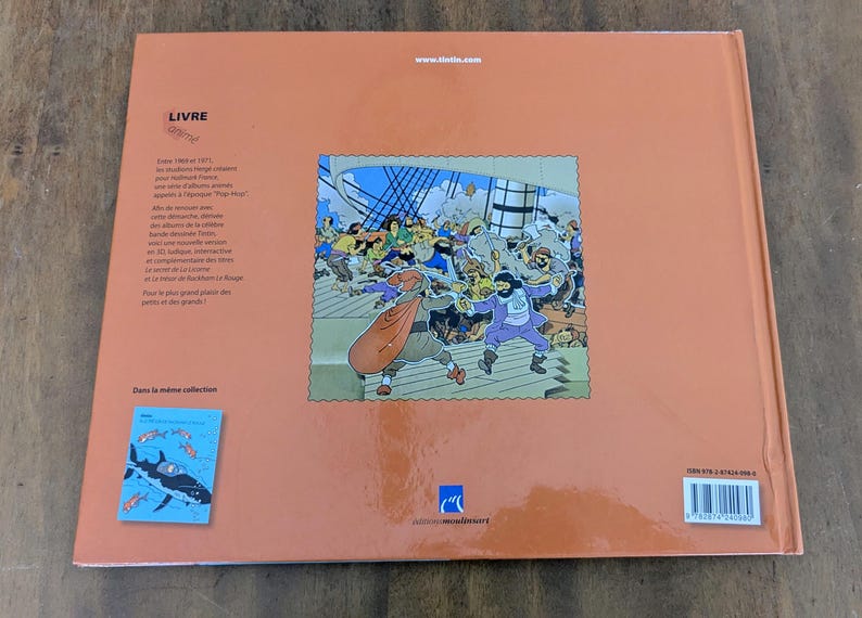 Puede incluir: Una contraportada de libro de color naranja claro con una ilustraci&oacute;n central de una pelea de espadas en la cubierta de un barco. Incluye texto en franc&eacute;s, un peque&ntilde;o gr&aacute;fico azul de un tibur&oacute;n, el sitio web tintin.com, un c&oacute;digo de barras y el logo de Casterman.