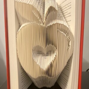 May include: A book with pages folded into a 3D sculpture of a pair of lips. The book is open and the sculpture is visible from the front.