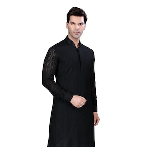 May include: A black long-sleeved kurta with intricate embroidery. The kurta has a mandarin collar and a button closure. The model is wearing white pants and gold shoes.