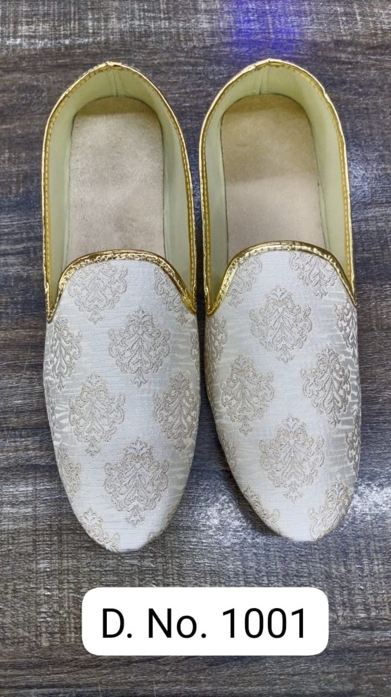 May include: A pair of white slip-on shoes with a gold trim and a white and gold patterned design. D. No. 1001