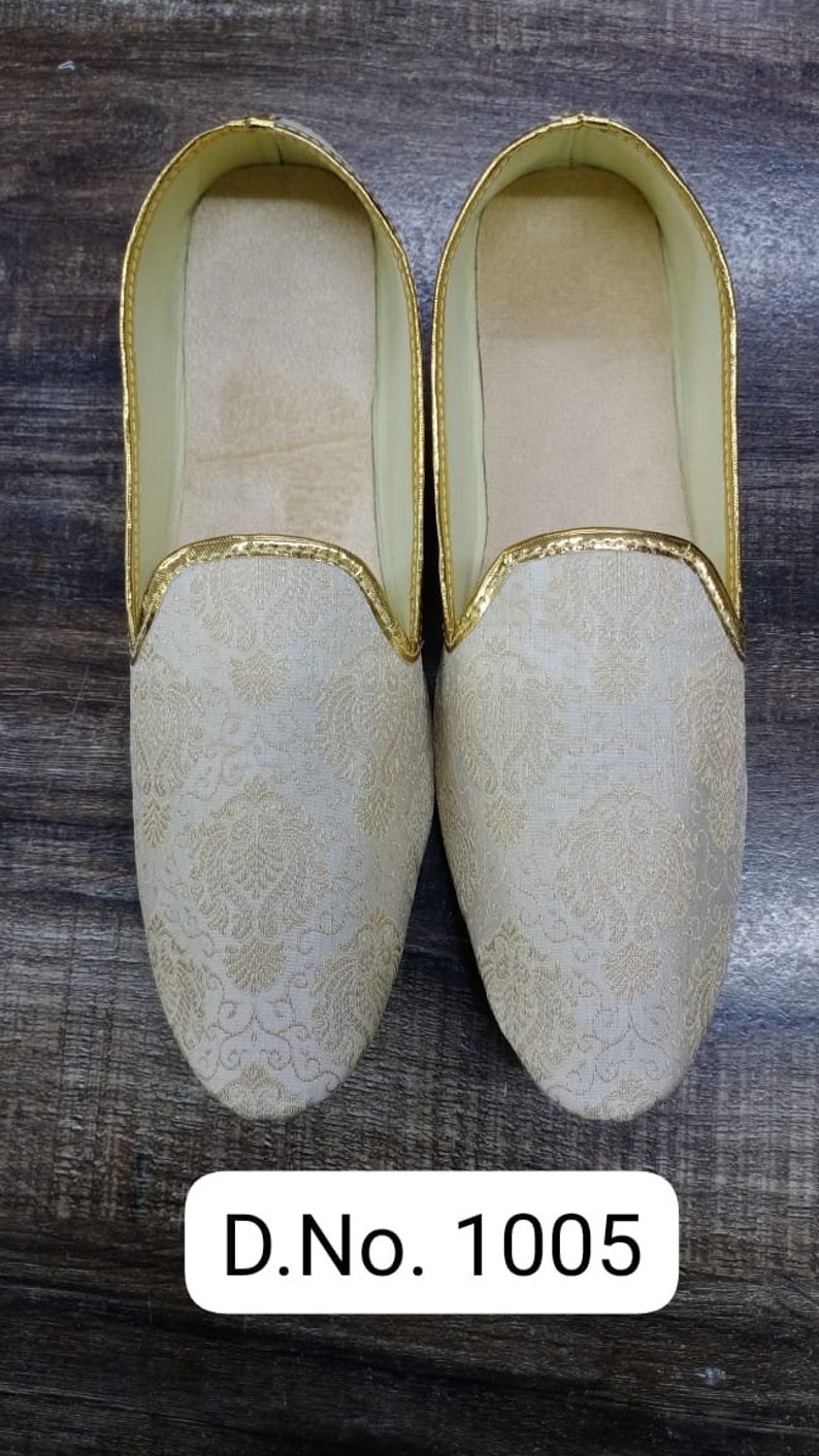 May include: A pair of white embroidered slippers with gold trim. The slippers have a pointed toe and a flat sole. D.No. 1005