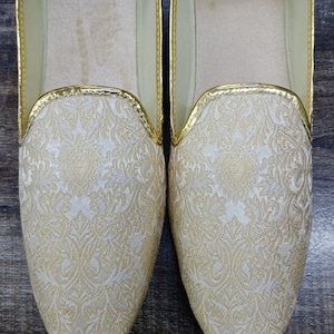 May include: A pair of white and gold embroidered slippers with a gold trim. D.No.1004
