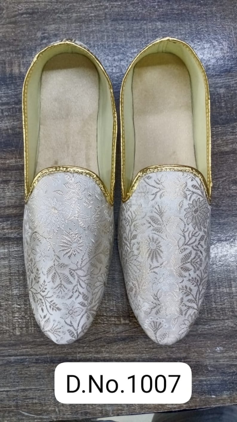 May include: A pair of white embroidered slippers with gold trim. The slippers have a floral pattern and are labeled "D.No.1007".