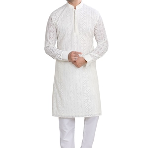 May include: A white long-sleeved kurta with intricate embroidery. The kurta has a mandarin collar and a button closure. The model is wearing white pants and beige shoes.