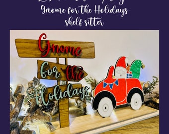 May include: Laser cut file/svg design for a wooden gnome shelf sitter. The gnome is driving a red car with a green tree on top. The sign reads "Gnome for the Holidays".