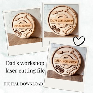 May include: A laser cut wooden sign with the text "Dad's Workshop" in a circle with gears and tools around it.