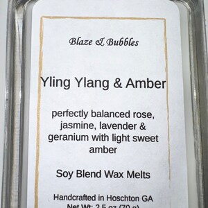 May include: A clear plastic container holding a white label with the text "Blaze & Bubbles." The label reads "Yling Ylang & Amber" and lists ingredients. The net weight is 2.5 oz (70 g).