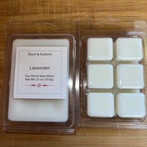 May include: Two clear plastic containers of soy blend wax melts. One container has a solid block of wax, the other has six individual cubes. The label reads "Blaze & Bubbles Lavender" and "Net Wt 2.5 oz (70.9g)".