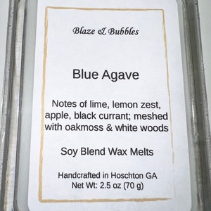 May include: A clear plastic package containing a label for "Blue Agave" soy blend wax melts. The label lists scent notes of lime, lemon zest, apple, and black currant. It is handcrafted in Hoschton, GA, and weighs 2.5 oz (70 g).