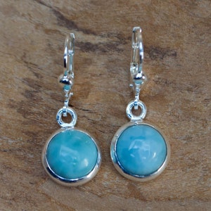 May include: A pair of silver dangle earrings with round blue gemstones.