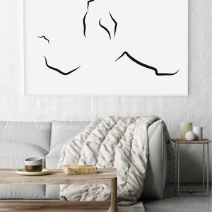 Puede incluir: Una impresi&oacute;n en blanco y negro de arte lineal de una pareja abraz&aacute;ndose. La impresi&oacute;n est&aacute; sobre un fondo blanco y est&aacute; enmarcada en un marco negro simple. La impresi&oacute;n est&aacute; colgada en una pared blanca sobre un sof&aacute; gris con una manta blanca.
