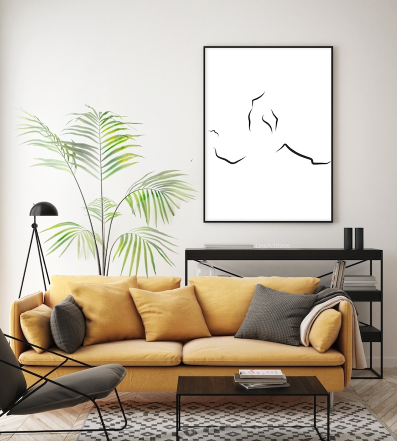 Puede incluir: Una impresi&oacute;n en blanco y negro de arte lineal de una pareja abraz&aacute;ndose, colgada en una pared blanca sobre un sof&aacute; amarillo con almohadas negras. La impresi&oacute;n est&aacute; enmarcada en un marco negro y tiene el texto "lineArtBabe" impreso debajo.