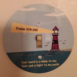 May include: A round light switch cover with a lighthouse illustration and the text "Psalm 119:105" and "Your word is a lamp to my feet and a light to my path".