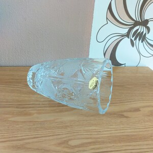 May include: A clear glass vase with a cut crystal design. The vase has a label that reads "Crystal Bohemia."