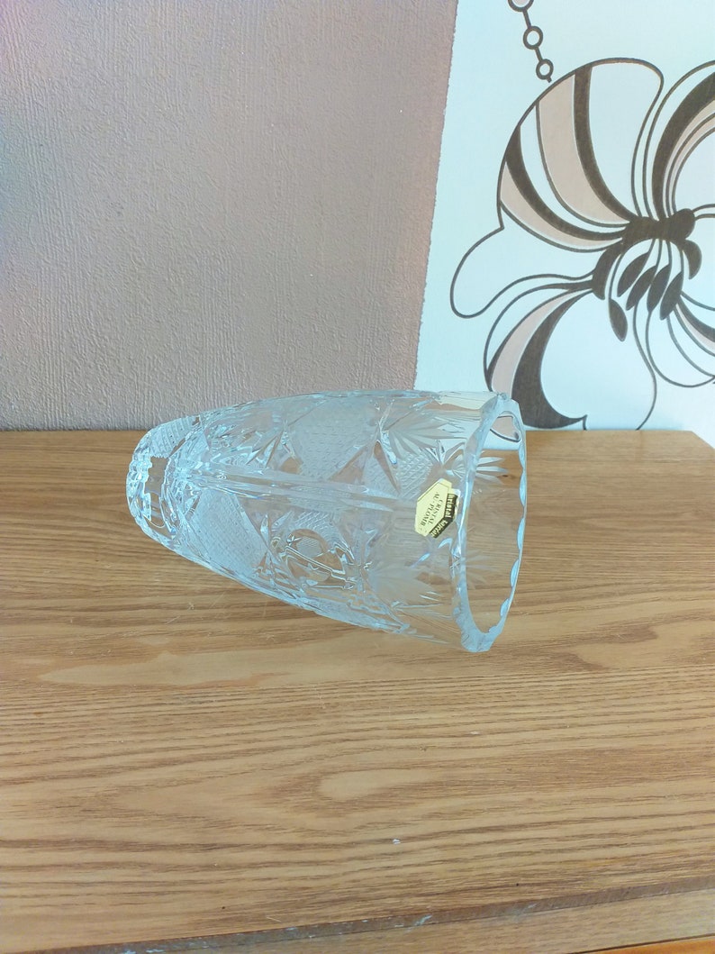 May include: A clear glass vase with a cut crystal design. The vase has a label that reads "Crystal Bohemia."