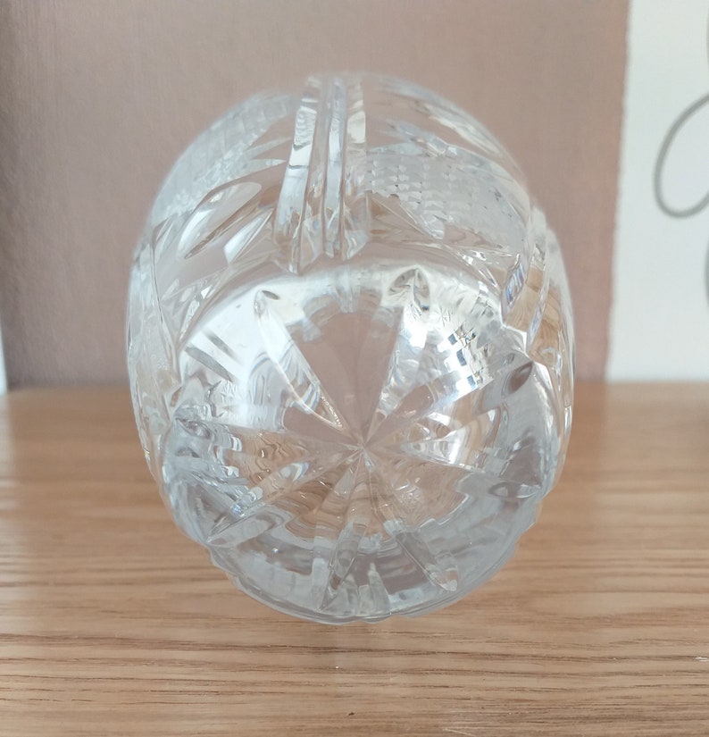 May include: A clear glass bottle stopper with a cut crystal design. The stopper is shaped like an egg and has a starburst pattern on the bottom.