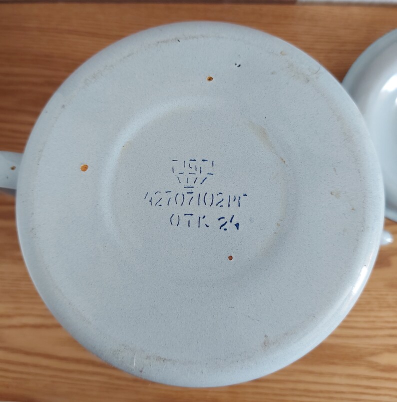 Może przedstawiać: Jasnoniebieski czajnik emaliowany z niebieskim napisem na spodzie, kt&oacute;ry brzmi "EIGH 1977 42707102PT OTK 2/4".